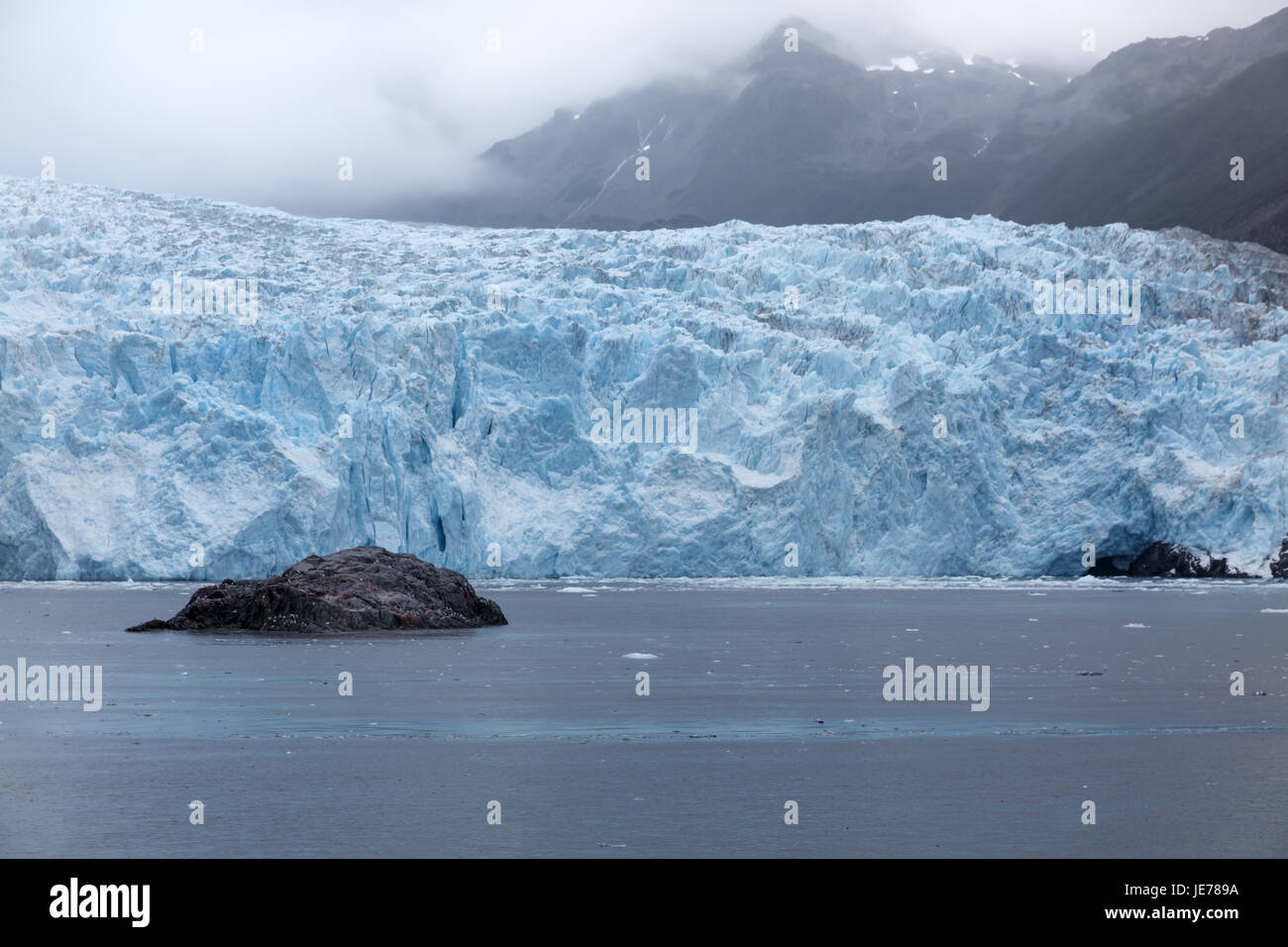 Gletscher am Rand des Ozeans mit Bergen im Hintergrund Stockfoto