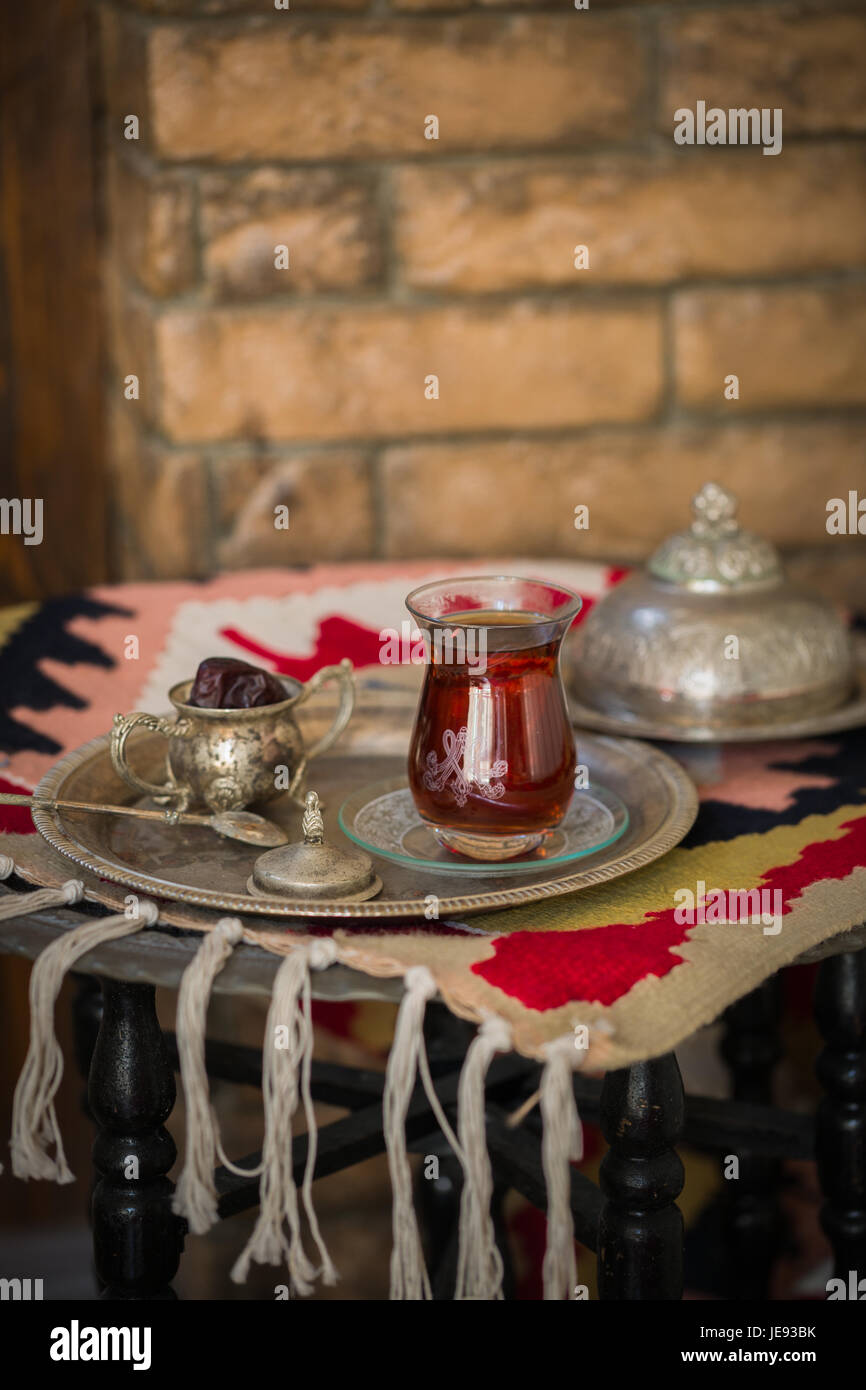 Tee-Set im orientalischen Stil in Birne geformt Glas mit Löffel und Vintage Wasserkocher und Termine Frucht auf silbernen Tablett auf silbernen Tablett gegen Mauer Stockfoto