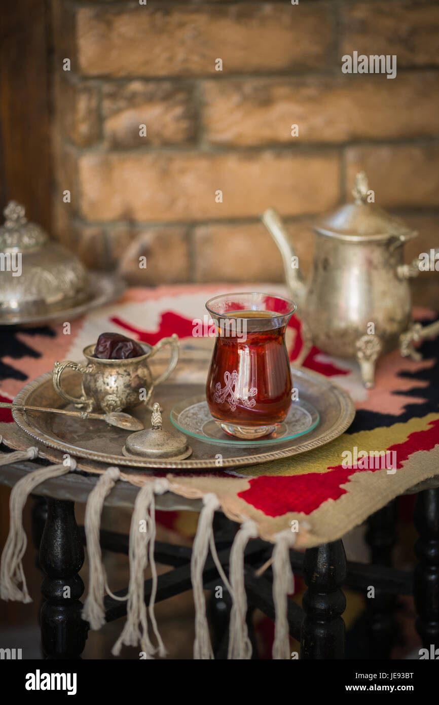 Tee-Set im orientalischen Stil in Birne geformt Glas mit Löffel und Vintage Wasserkocher und Termine Frucht auf silbernen Tablett auf silbernen Tablett gegen Mauer Stockfoto