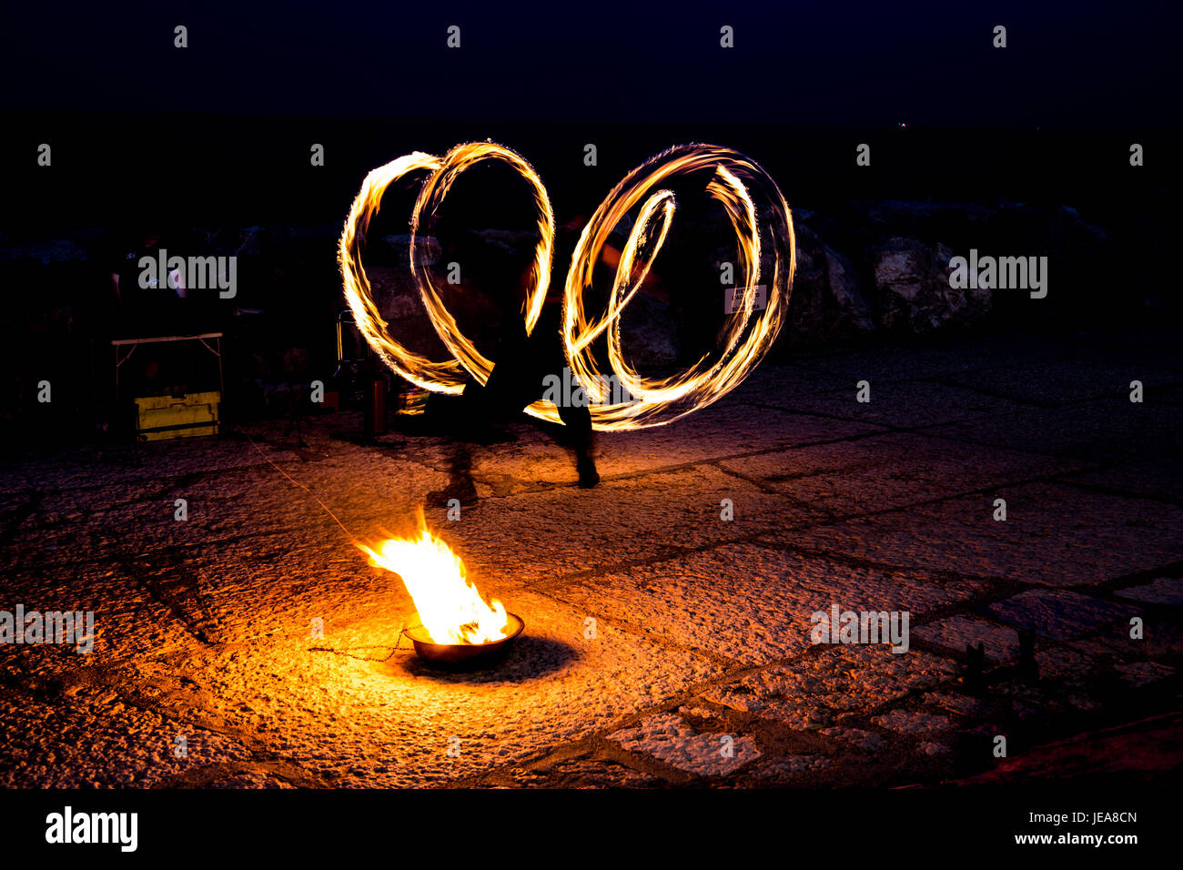 Streetart-Künstler mit einem brennenden Stock während seiner gefährlichen Feuershow Stockfoto