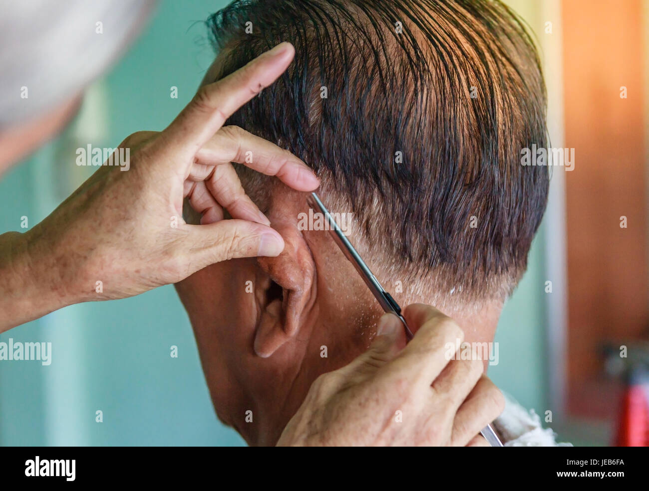 Meister schneidet Haare und Bart von Männern im Frisörsalon, macht Friseur Frisur für einen senior asiatischen Mann Stockfoto