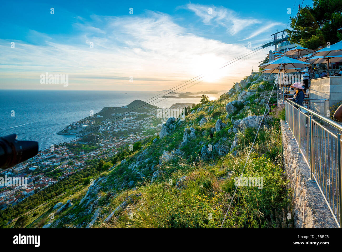 Sonnenuntergang Blick auf die obere Station der Dubrovnik Seilbahn. Touristen drängen Cafés und ein Restaurant, um den Sonnenuntergang zu beobachten. Stockfoto