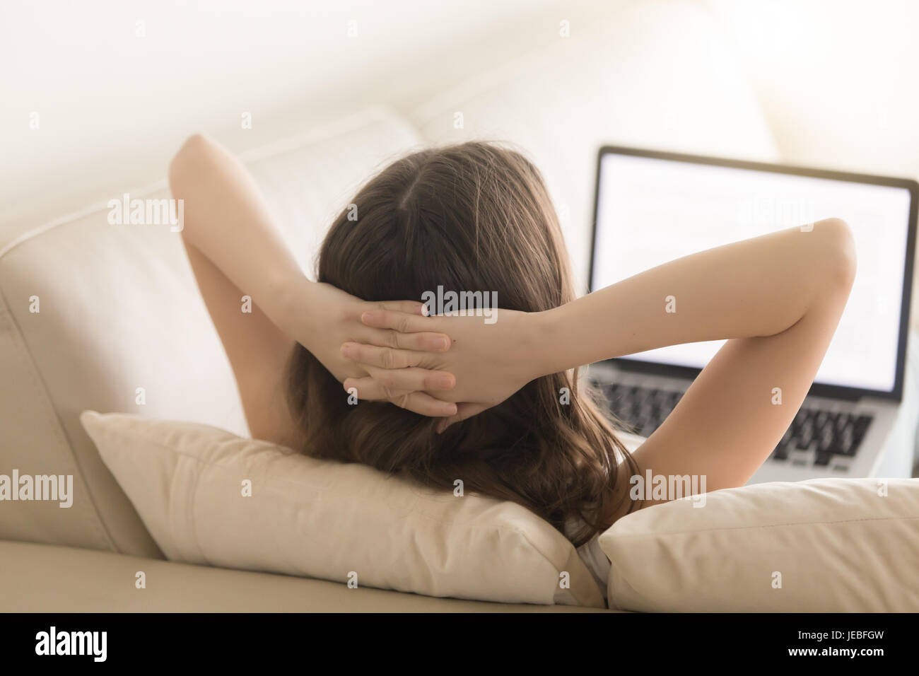 Entspannte Frau liegt auf Sofa und Blick auf laptop Stockfoto