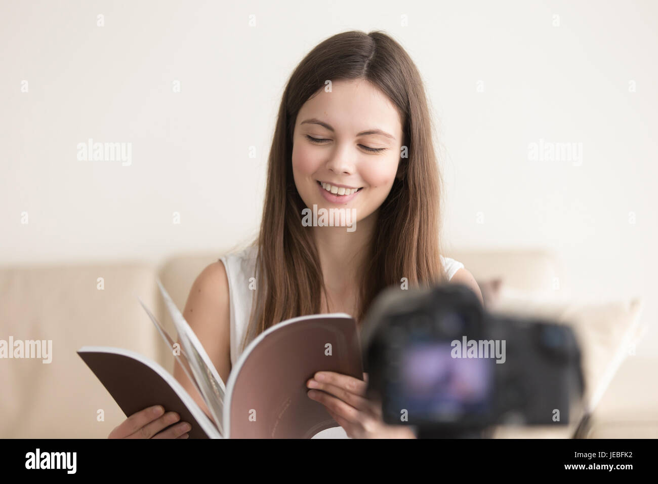 Lächelndes Teen Mädchen mit Buch Aufnahme vlog Stockfoto