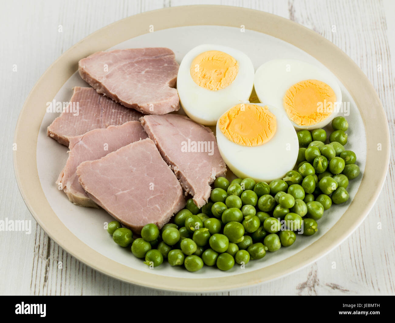 Gekochter Schinken und Ei-Salat mit grünen Garten Erbsen auf einem weißen texturiert Tischplatte Stockfoto