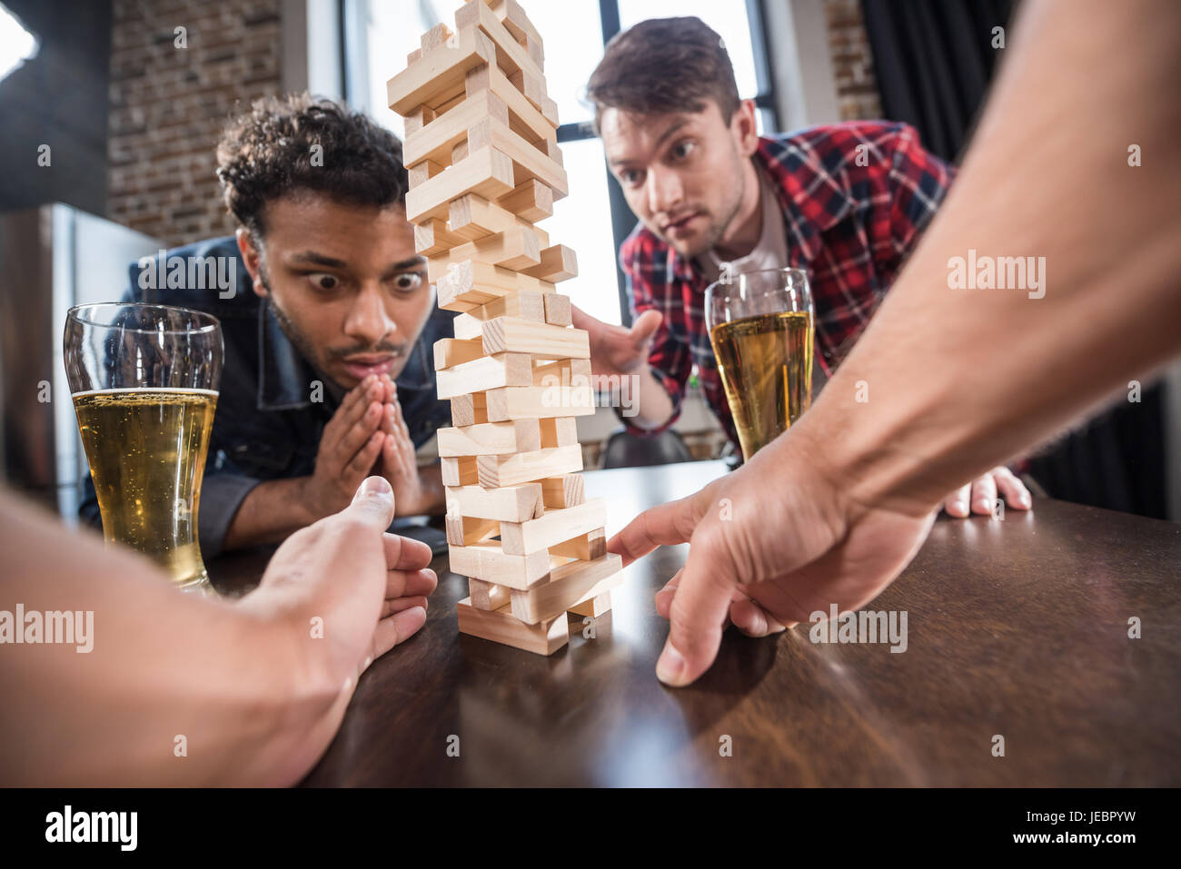 junge Männer Bier trinken und Jenga-Spiel zu spielen. junge Leute, die Spaß Konzept Stockfoto
