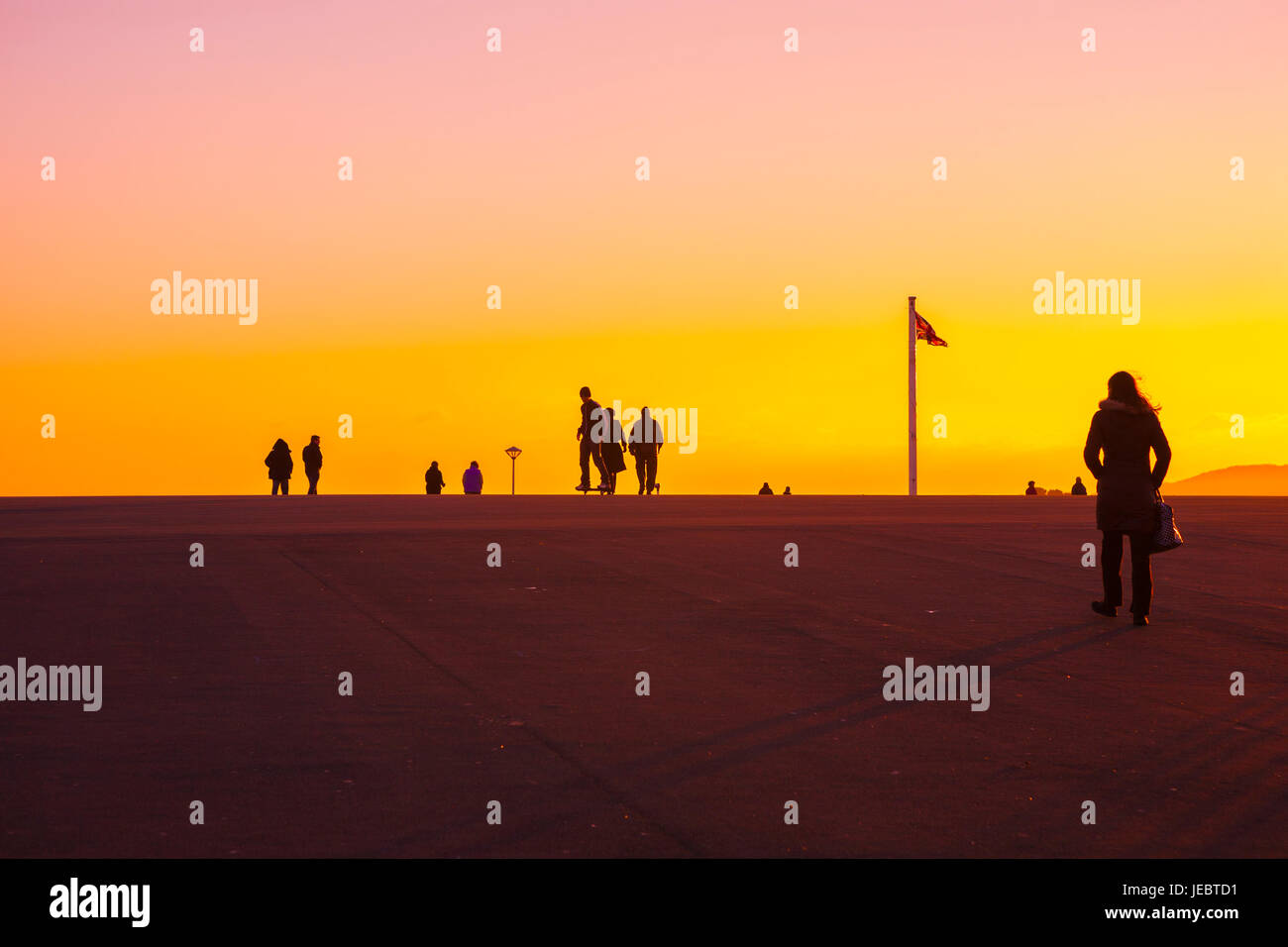 Silhouette Frau weibliche zu Fuß in goldenen Sonnenuntergang auf Promenade, Plymouth Hacke, Devon, England, UK Stockfoto