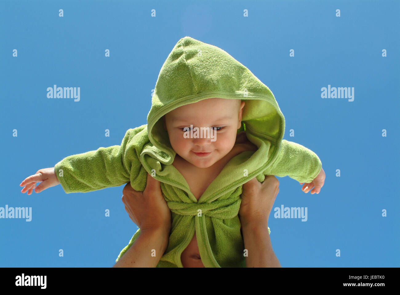 6 Monate altes Baby wird von Eltern, fröhlich, lachen, blauen Himmel gehoben, Stockfoto
