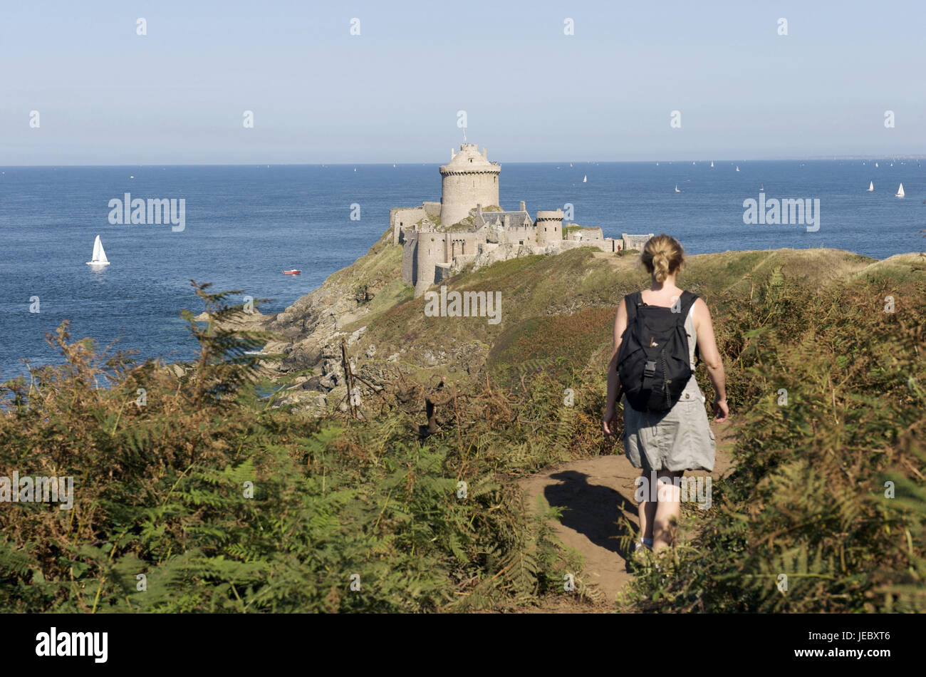 Europa, Frankreich, Bretagne, Cote D' Emeraude, Cap Frehel, Frau auf Fußweg, im Hintergrund die Festung la Schlossbar Stockfoto