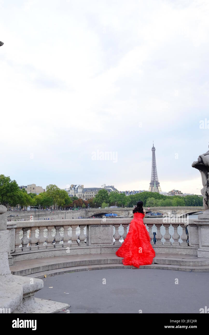 Eine Frau in einem langen roten Kleid oder Kleid, Blick auf den Eiffelturm in Paris Stockfoto
