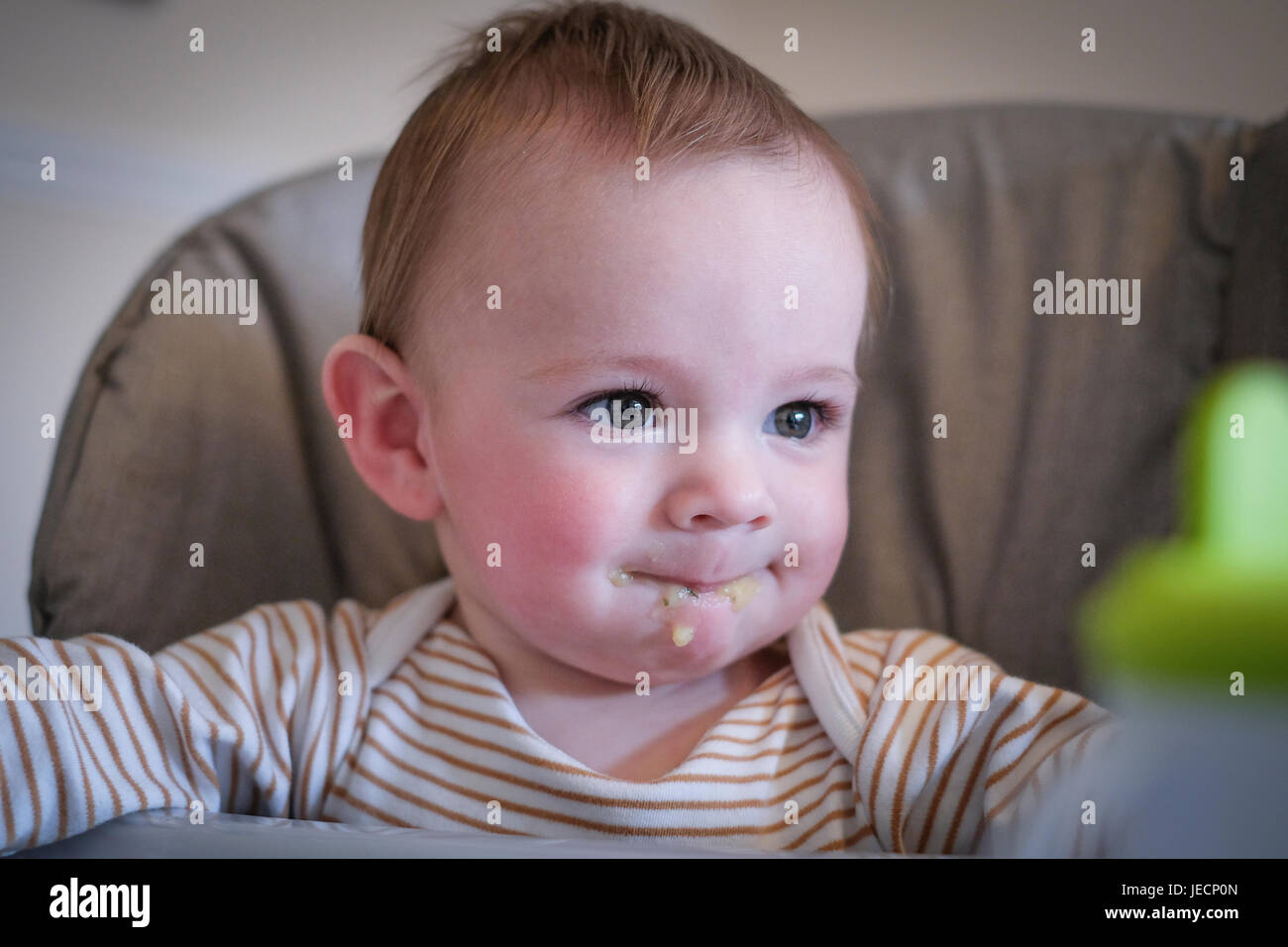 Baby Junge im Hochstuhl mit Essen auf Gesicht Stockfoto