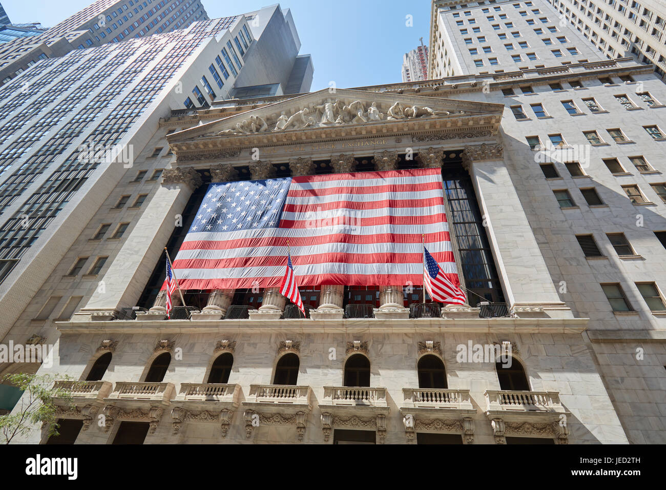 Wall Street Börse niedrigen Winkel anzeigen mit großen US-Flagge, Bankenviertel in New York an einem sonnigen Tag Stockfoto