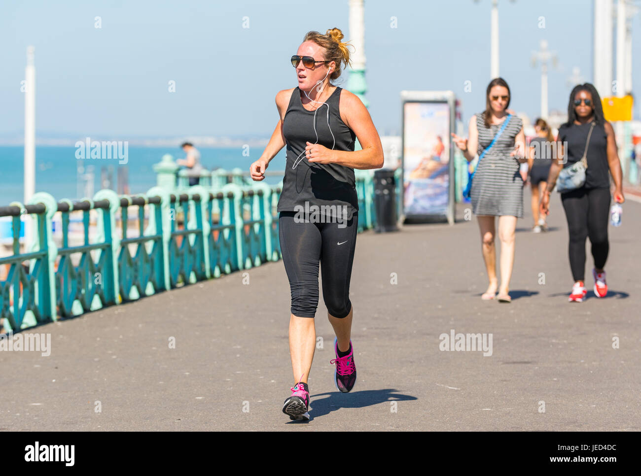 Junge Frau Joggen entlang der Strandpromenade an einem heißen Tag im Sommer. Stockfoto