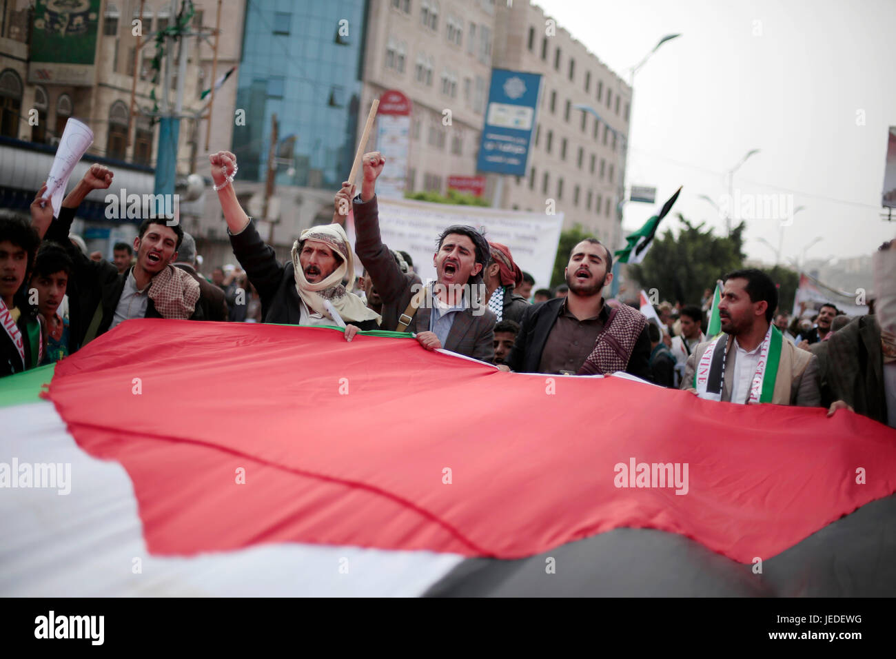 Anhänger der Huthi-Rebellen schreien Parolen, wie sie die palästinensische nationale Fahne während einer Demonstration anlässlich Quds Day (Jerusalem-Tag) in Sanaa, Jemen, 23. Juni 2017 tragen. Quds Day findet am letzten Freitag des muslimischen Fastenmonats Ramadan statt. Die Veranstaltung wurde vom Iran 1979, Unterstützung für die Palästinenser initiiert. Foto: Hani Al-Ansi/dpa Stockfoto