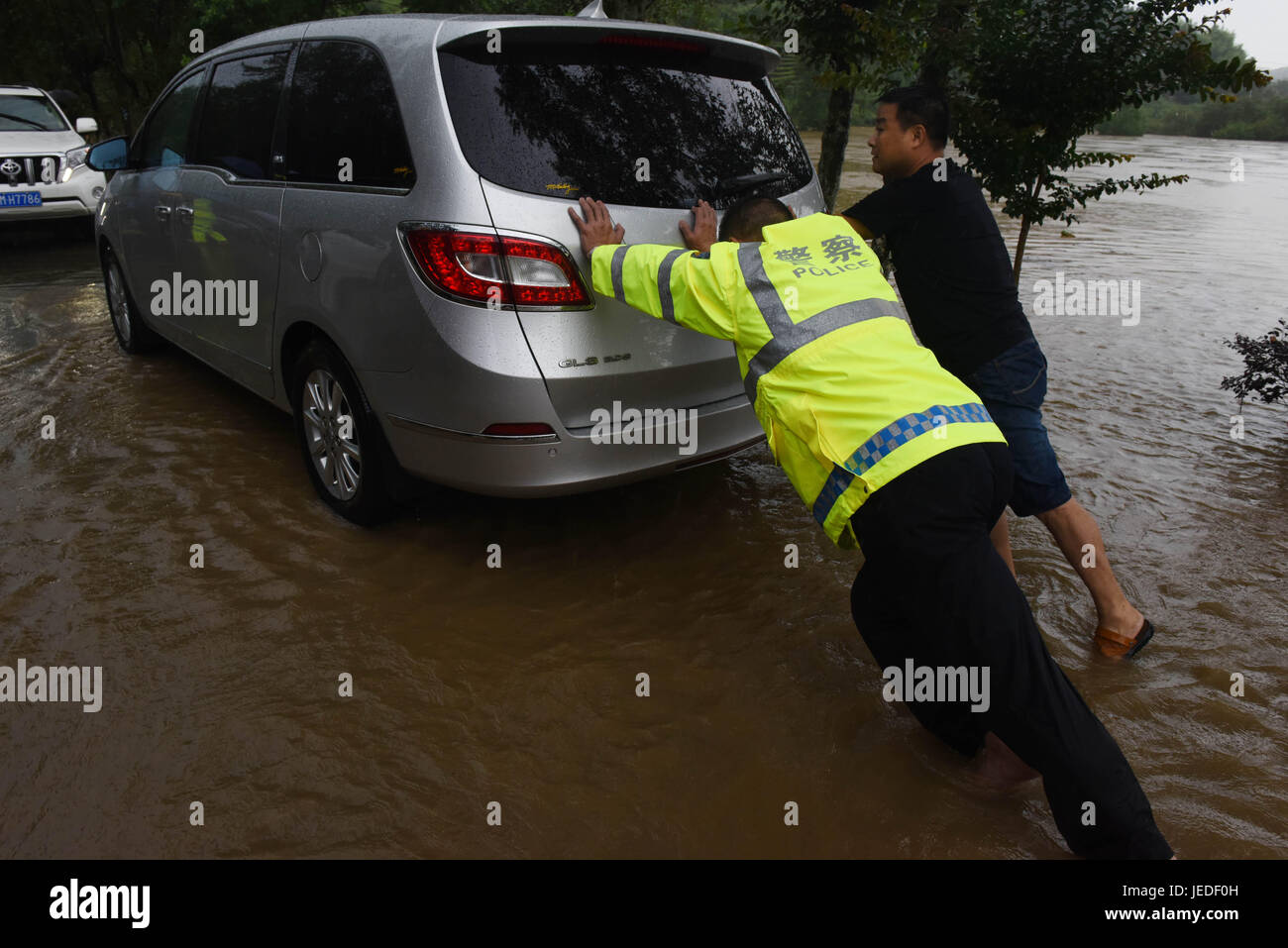 WUYUAN, Chinas Jiangxi Provinz. 24. Juni 2017. Verkehrspolizist hilft einen Fahrer ein Auto in einer überfluteten Straße in Wuyuan, Osten Chinas Jiangxi Provinz, 24. Juni 2017 drängen. Die Jiangxi Provinz Wetter Sternwarte am Samstag ausgestellt ein rotes Warnsymbol für Regen, das höchste Niveau in der vierstufige Wetter-Warnsystem. Starker Regen seit Dienstag hat die Evakuierung von 14.000 Menschen an sicherere Orte gezwungen. Bildnachweis: Song Zhenping/Xinhua/Alamy Live-Nachrichten Stockfoto