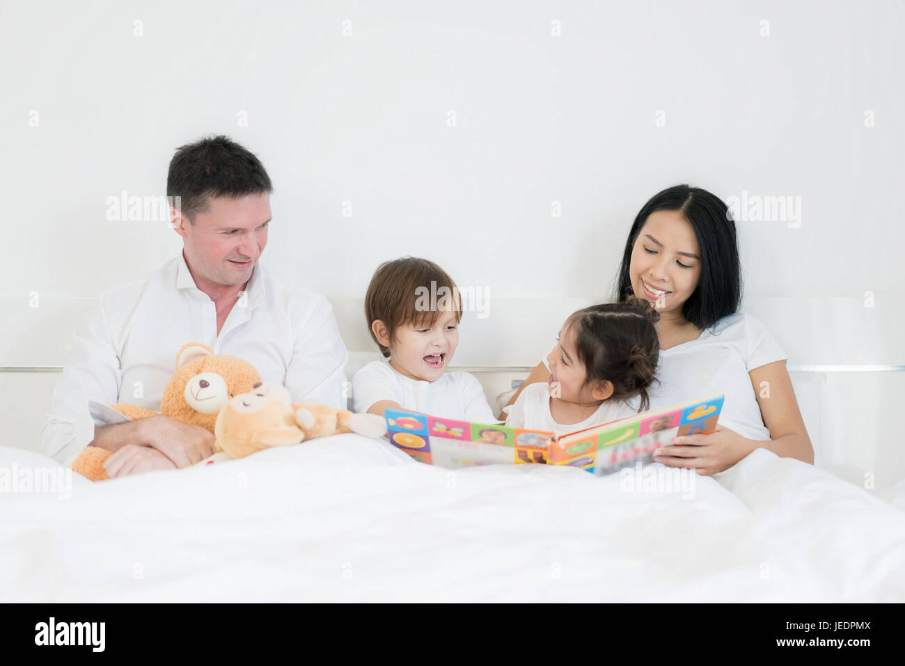 Asiatischen Brüder und asiatische Tochter Lesebuch zusammen im Bett im Schlafzimmer mit Vater und Mutter. Glückliche Familien-Konzept. Stockfoto