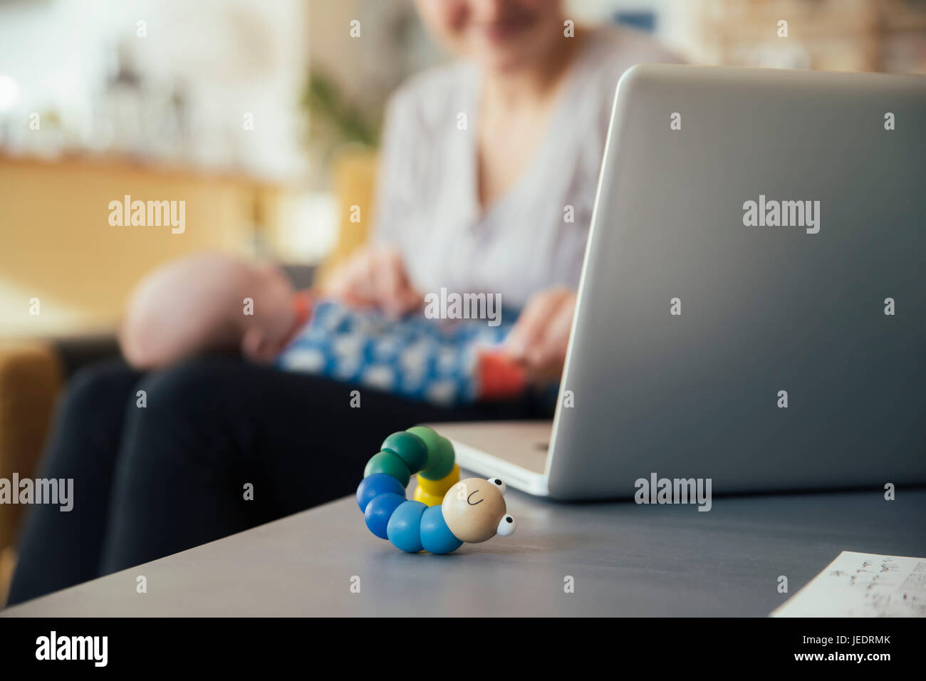 Baby Spielzeug neben Laptop Mutter hält ihr neugeborenes Baby zu Hause Stockfoto