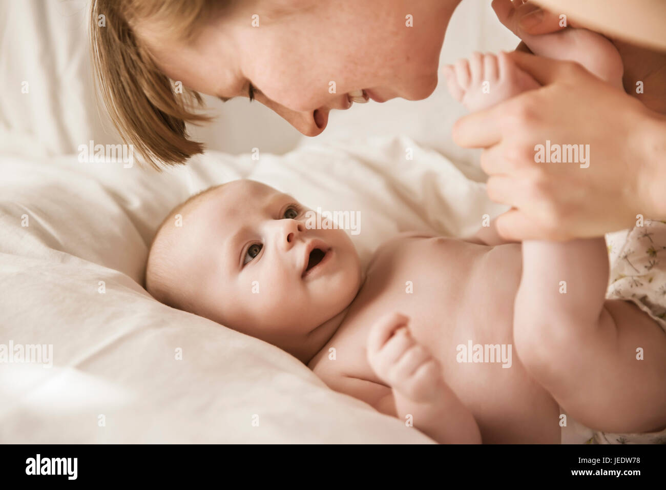 Glückliche Mutter Blick auf ihr Baby im Bett liegend Stockfoto