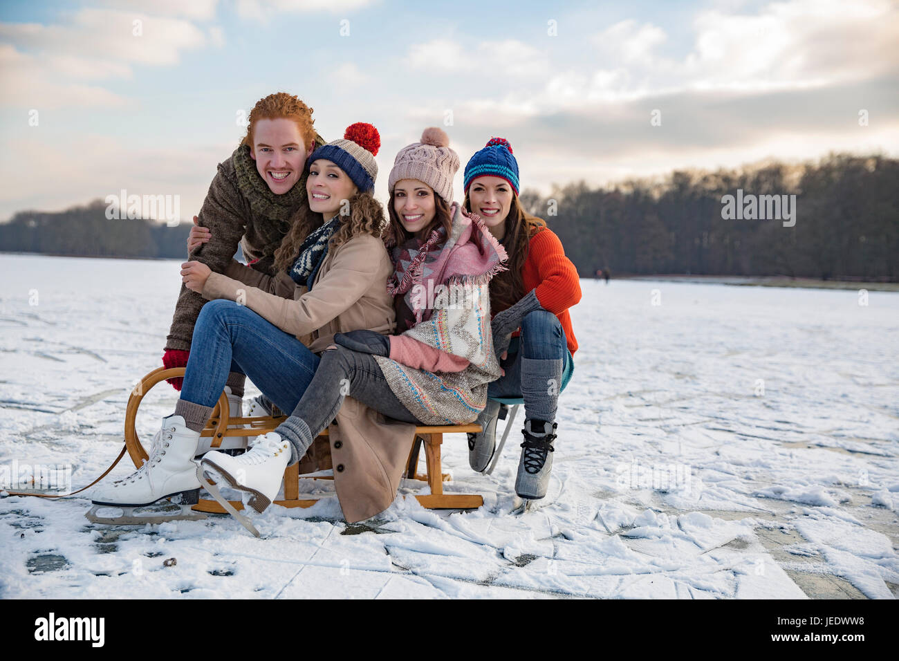 Freunde, die Spaß mit Schlitten auf zugefrorenen See Stockfoto
