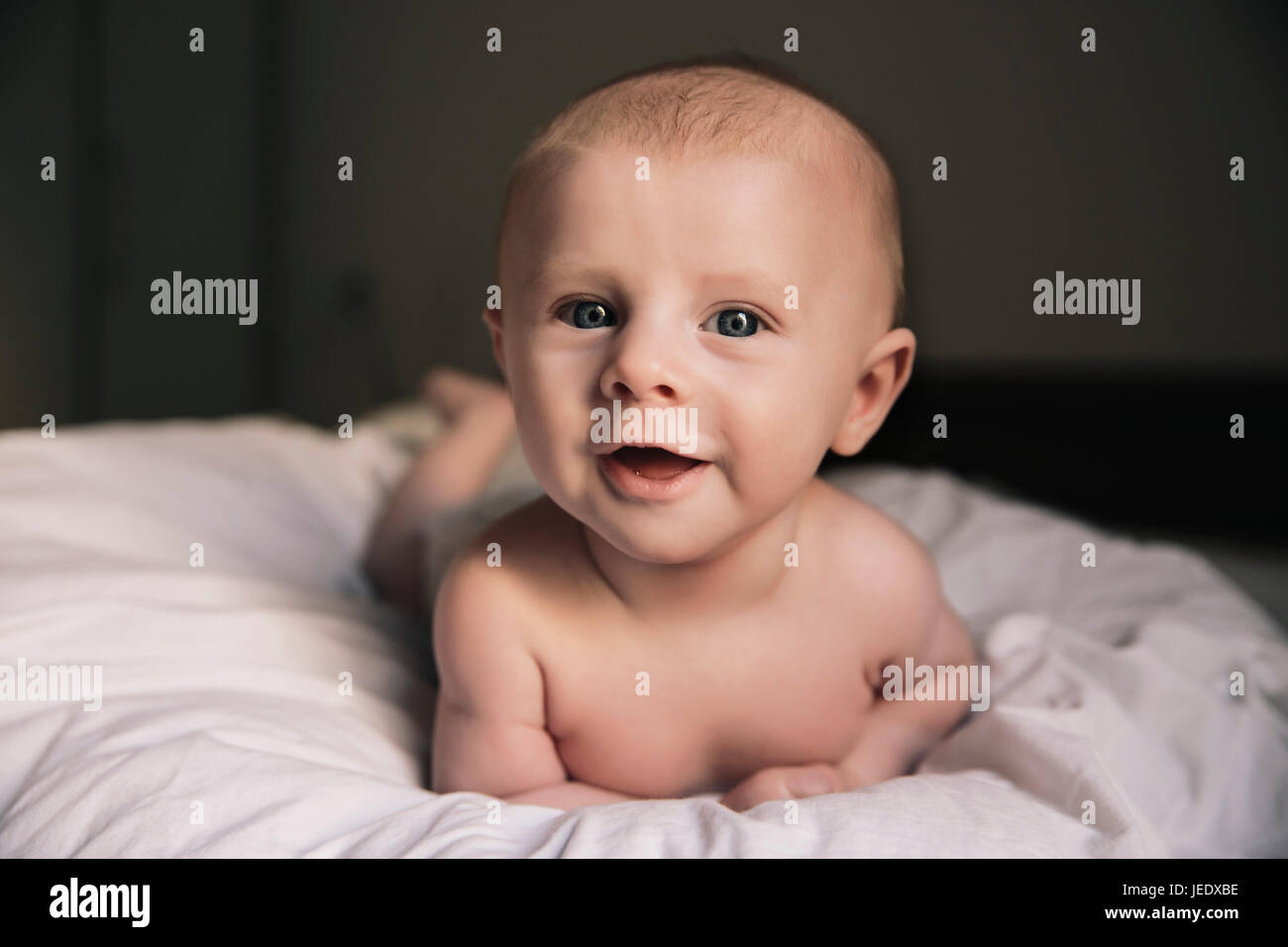 Porträt des Lachens Babyjungen auf Bett liegend Stockfoto