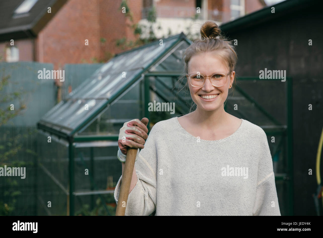 Porträt der lächelnde junge Frau vor Gewächshaus Stockfoto