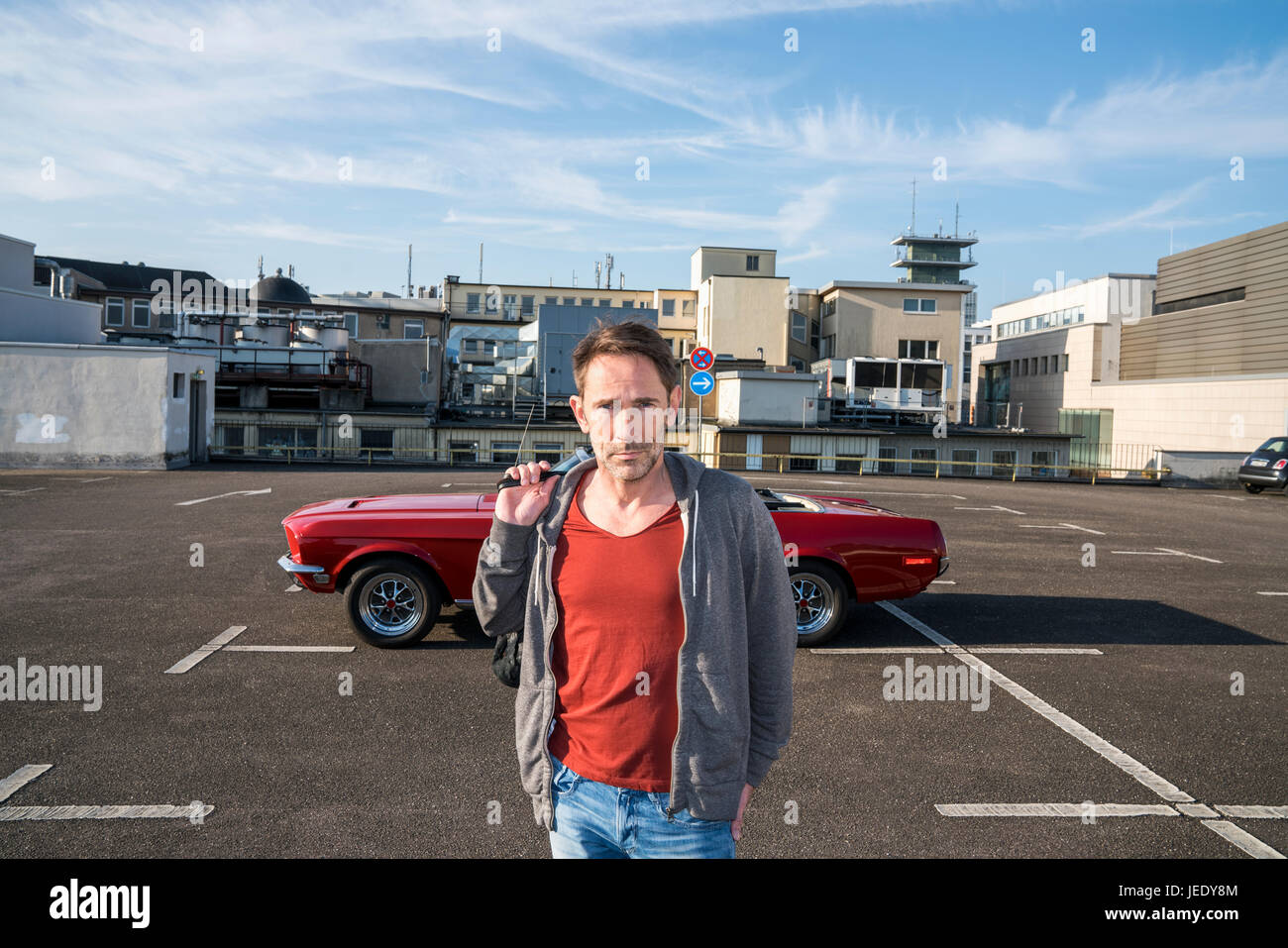 Porträt von reifer Mann vor seinem Sportwagen auf Parkdeck Stockfoto