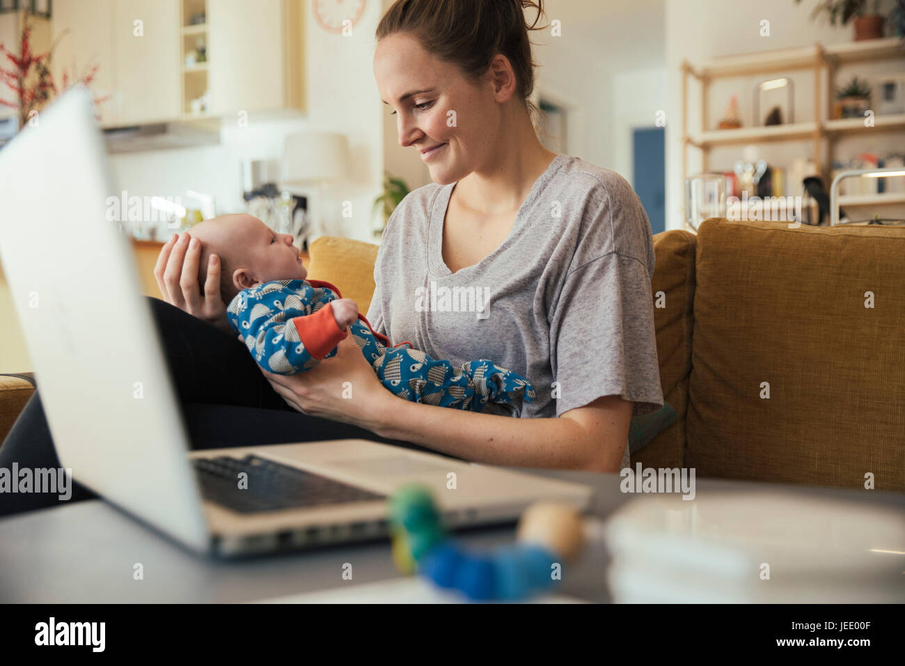 Mutter mit ihrem Neugeborenen Baby zu Hause neben laptop Stockfoto