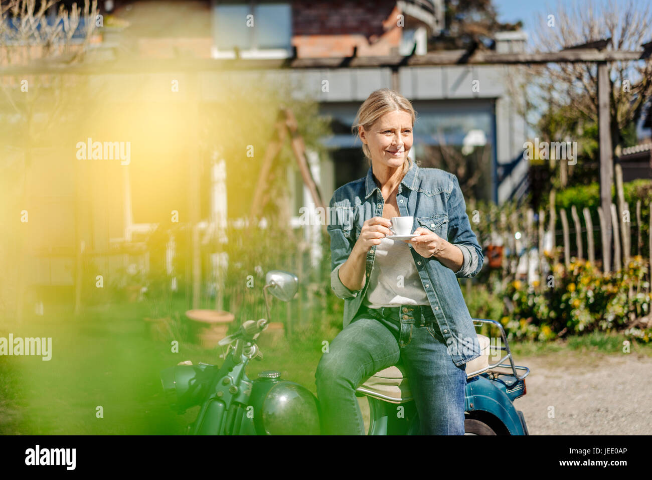 Lächelnde Frau auf Oldtimer Motorrad mit einer Kaffeepause Stockfoto