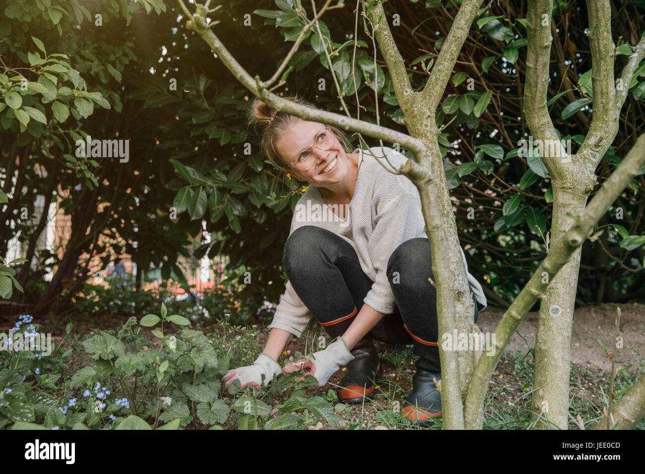 Lächelnde junge Frau clearing Unkraut im Garten Stockfoto