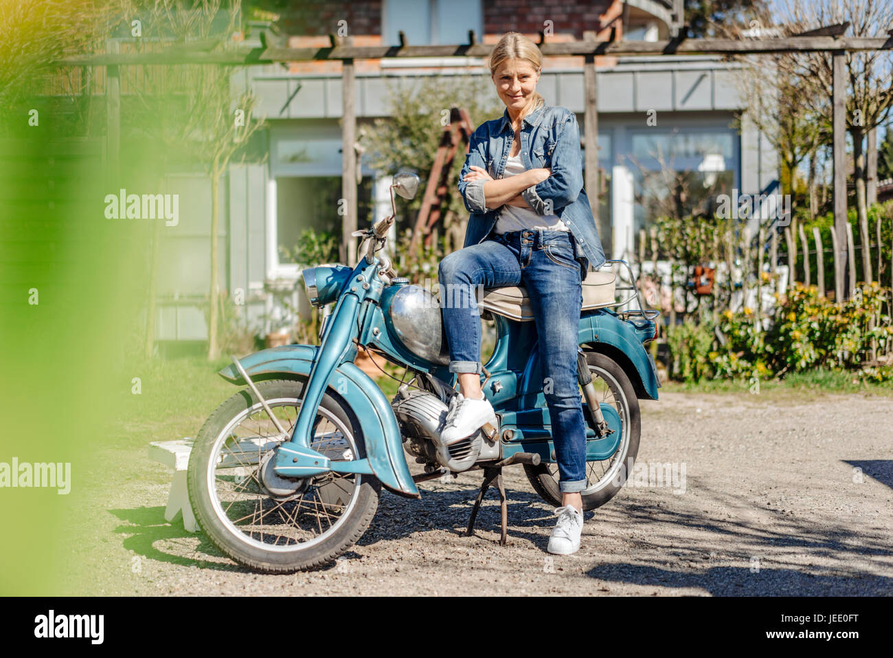 Lächelnde Frau mit Oldtimer Motorrad Stockfoto