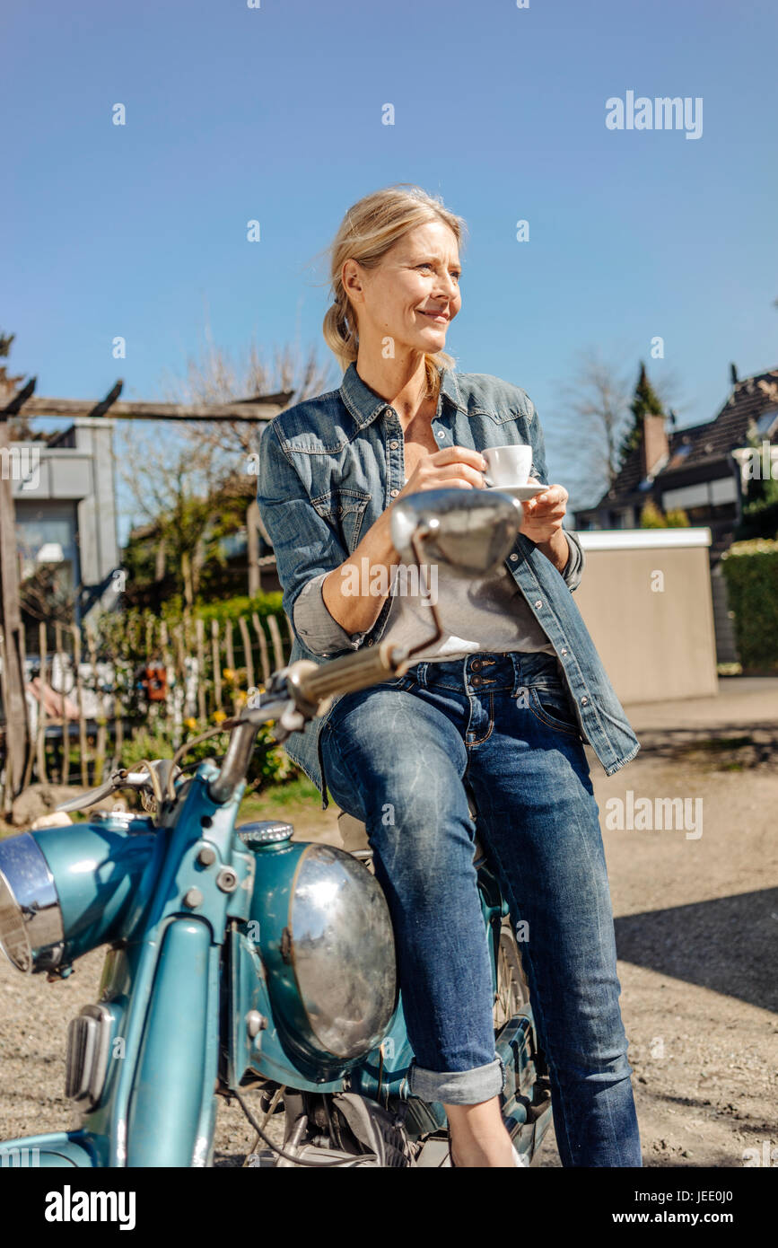 Lächelnde Frau mit Oldtimer Motorrad mit einer Kaffeepause Stockfoto