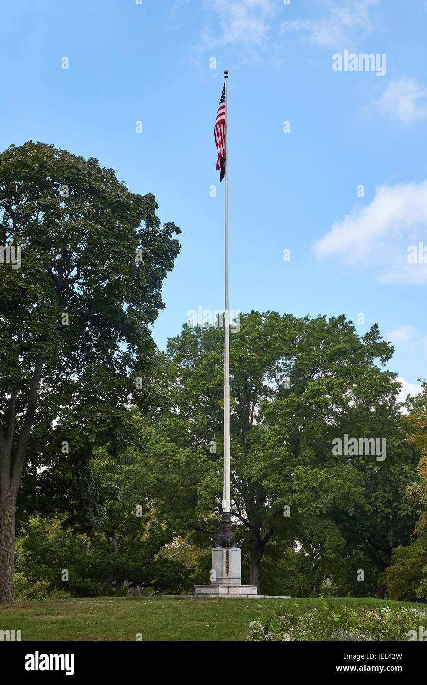 Amerikanische Flagge auf einem Mast mit einer Kugel auf der Spitze, zwischen grünen Bäumen gold steht gemacht Stockfoto