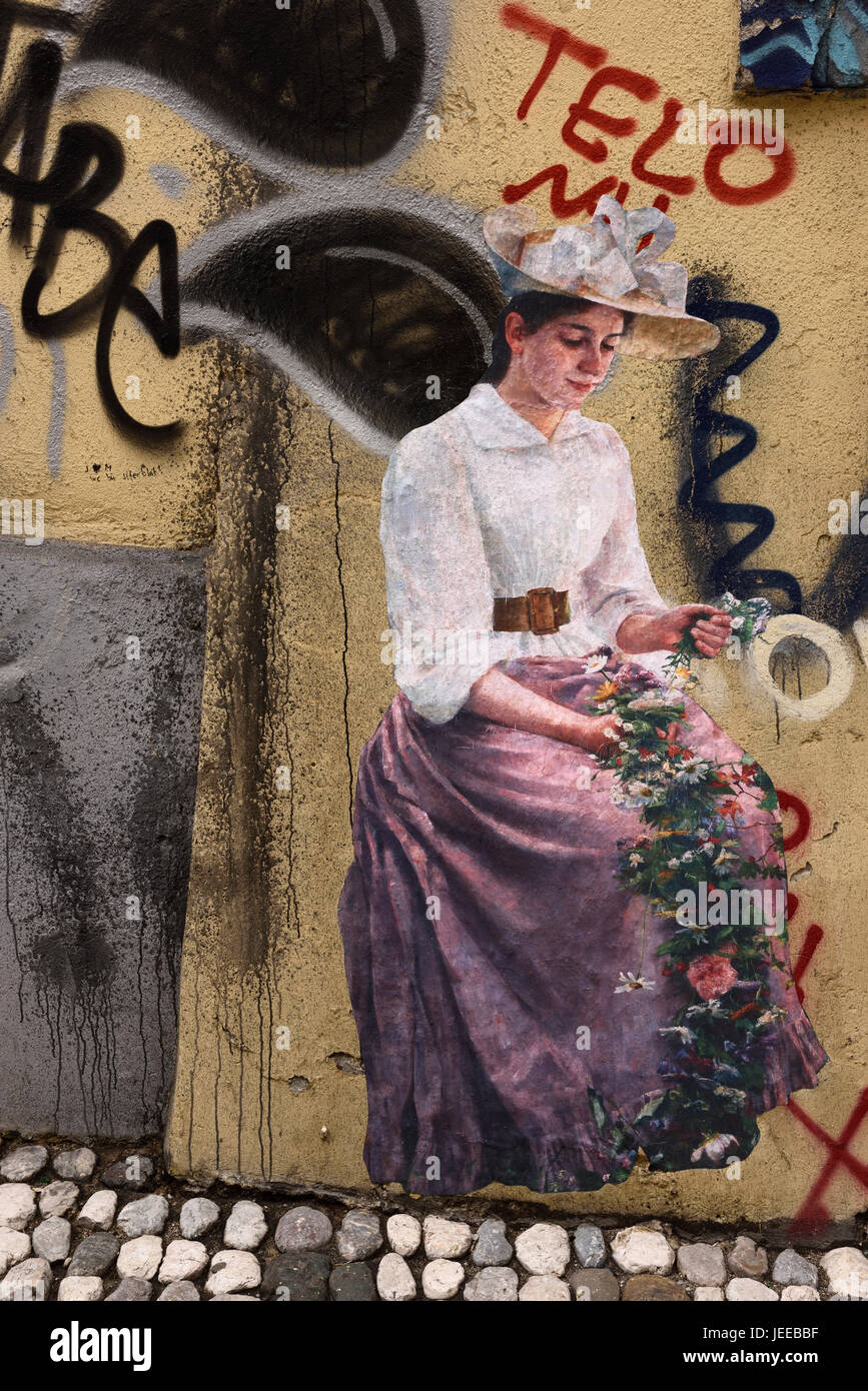 Fresko-Bild von einer Frau in traditioneller Kleidung mit Blumen unter Graffiti in einer Gasse in der historischen alten Stadt Zentrum von Ljubljana Slowenien Stockfoto