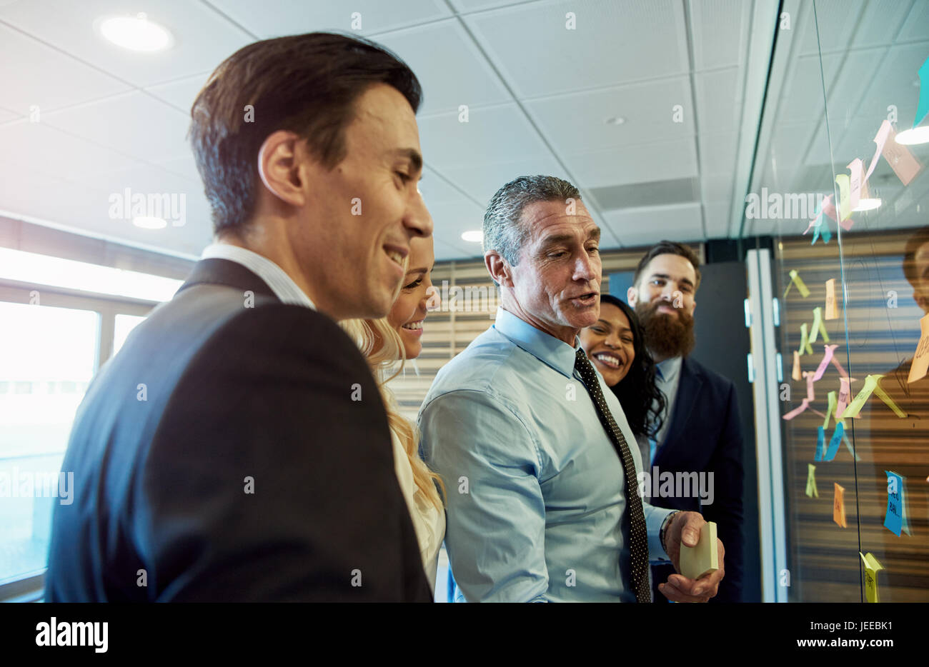 Multirassischen Business Team die Entwicklung eines neuen Projekts stehen rund um bunte klebrige Memos mit Ideen auf einer Glasoberfläche Lachen und Lächeln gruppiert Stockfoto