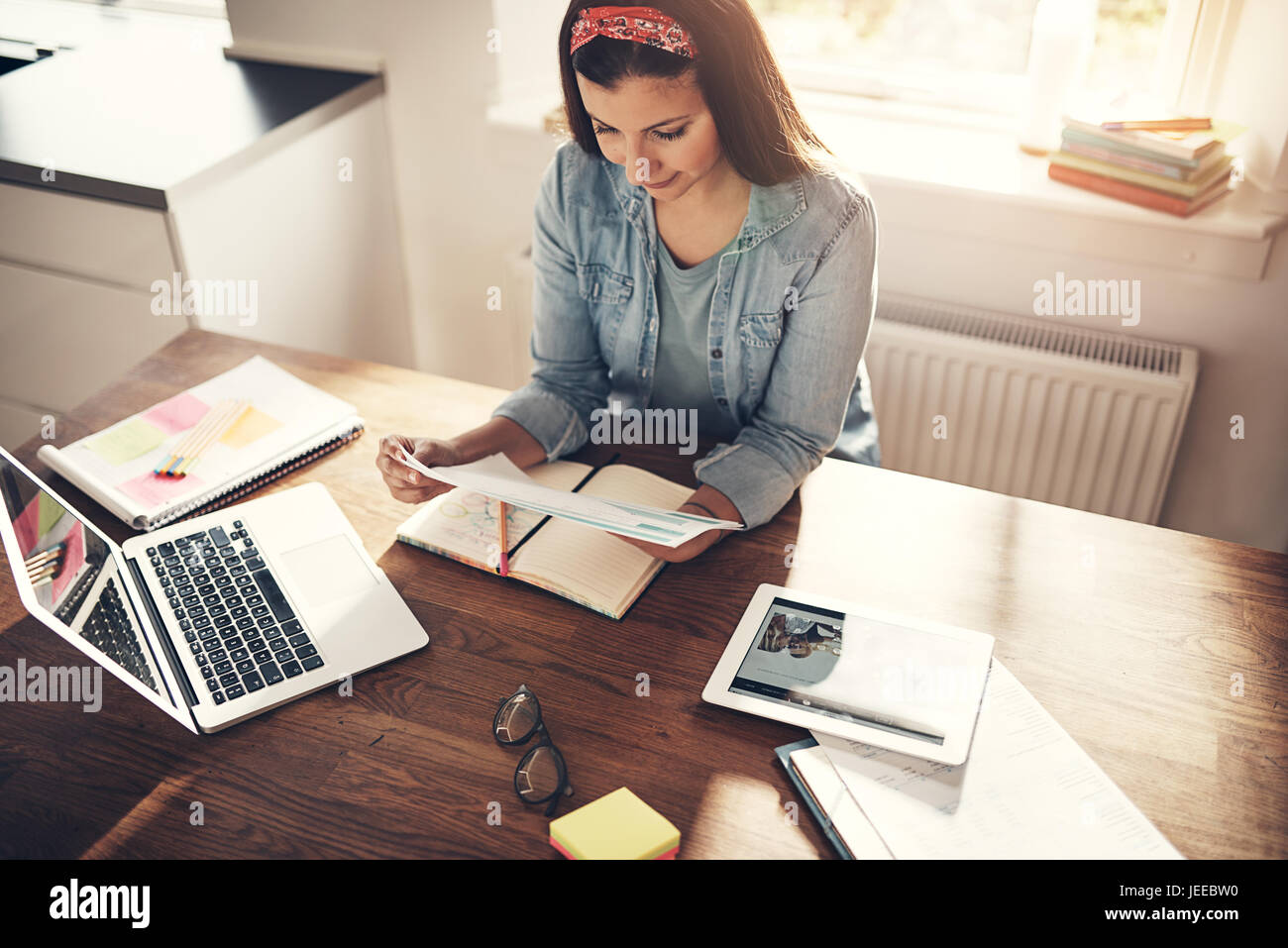 Hübsche junge Geschäftsfrau am Arbeitsplatz im Büro sitzen und arbeiten mit Dokumenten. Stockfoto