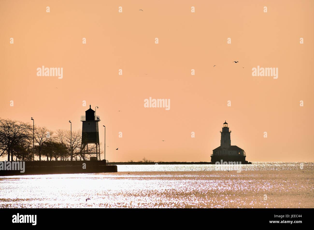 Frühe haze bleibt in den Himmel nach Sonnenaufgang eine Silhouette des Chicago Hafen Leuchtturm und einen Kanal Marker zur Verfügung zu stellen. Chicago, Illinois, USA. Stockfoto
