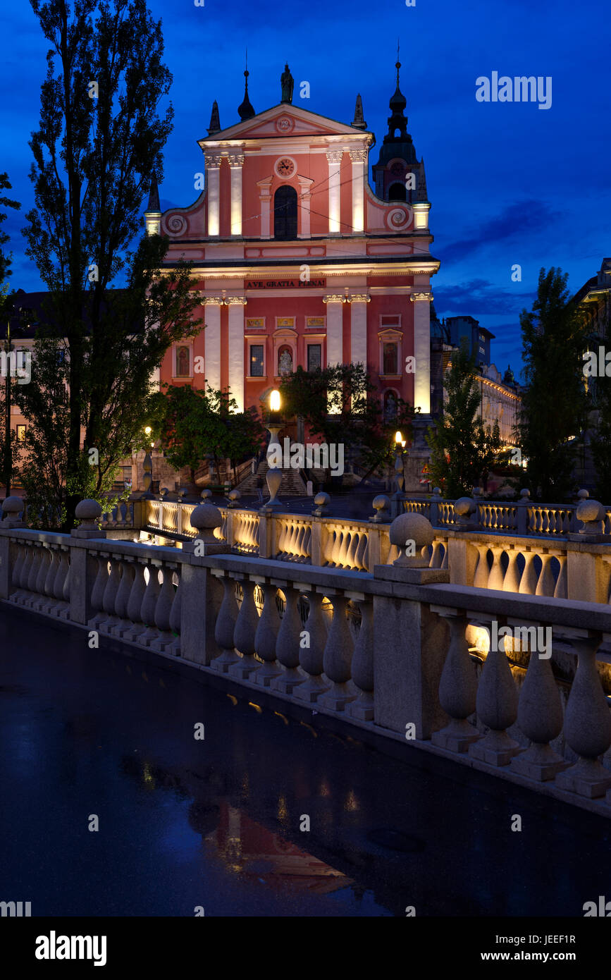 Rosa Fassade des Franziskaner-Kirche der Mariä Verkündigung in der Abenddämmerung mit Beton Balustraden Triple Bridge entworfen von Joze Plecnik Ljubljana Slowenien Stockfoto