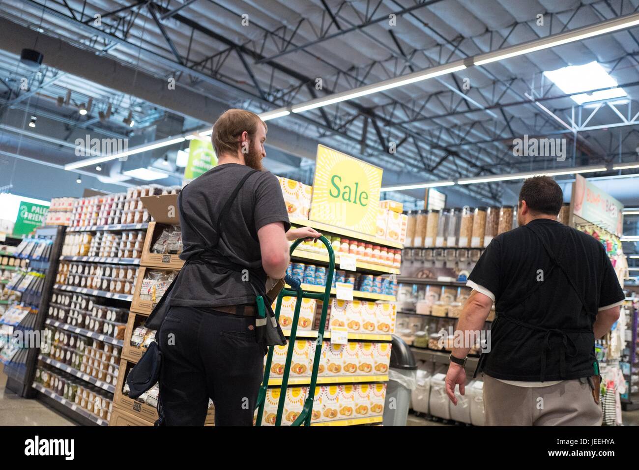 Zwei Mitarbeiter gehen vorbei an einem Schild mit der Aufschrift "Sale" im Supermarkt Whole Foods Market in Dublin, Kalifornien, 16. Juni 2017. Stockfoto