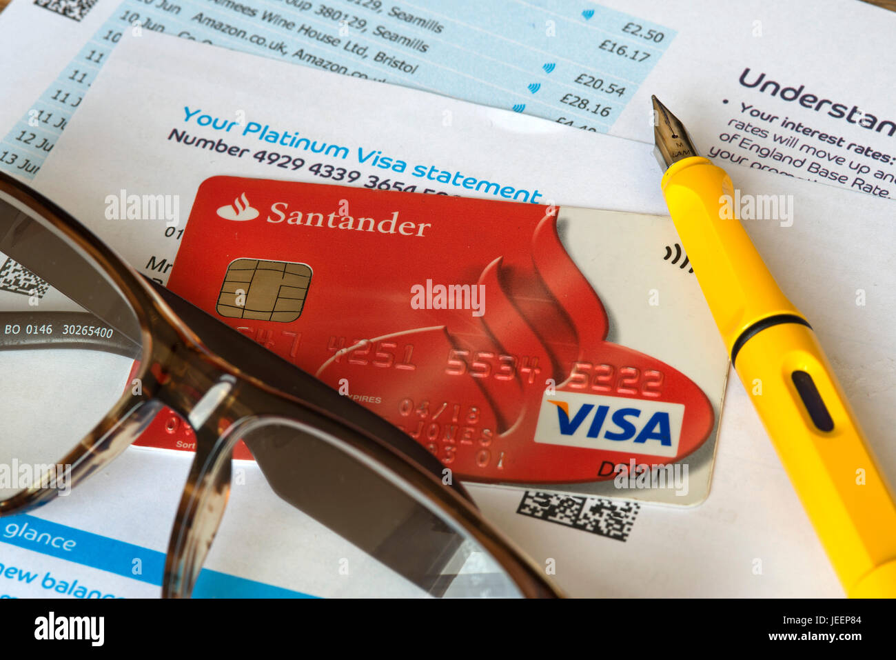 Santander-EC-Karte und Barclays Platin Visa Kreditkarten-Kontoauszug mit ein paar Gläsern und Füllfederhalter. Stockfoto