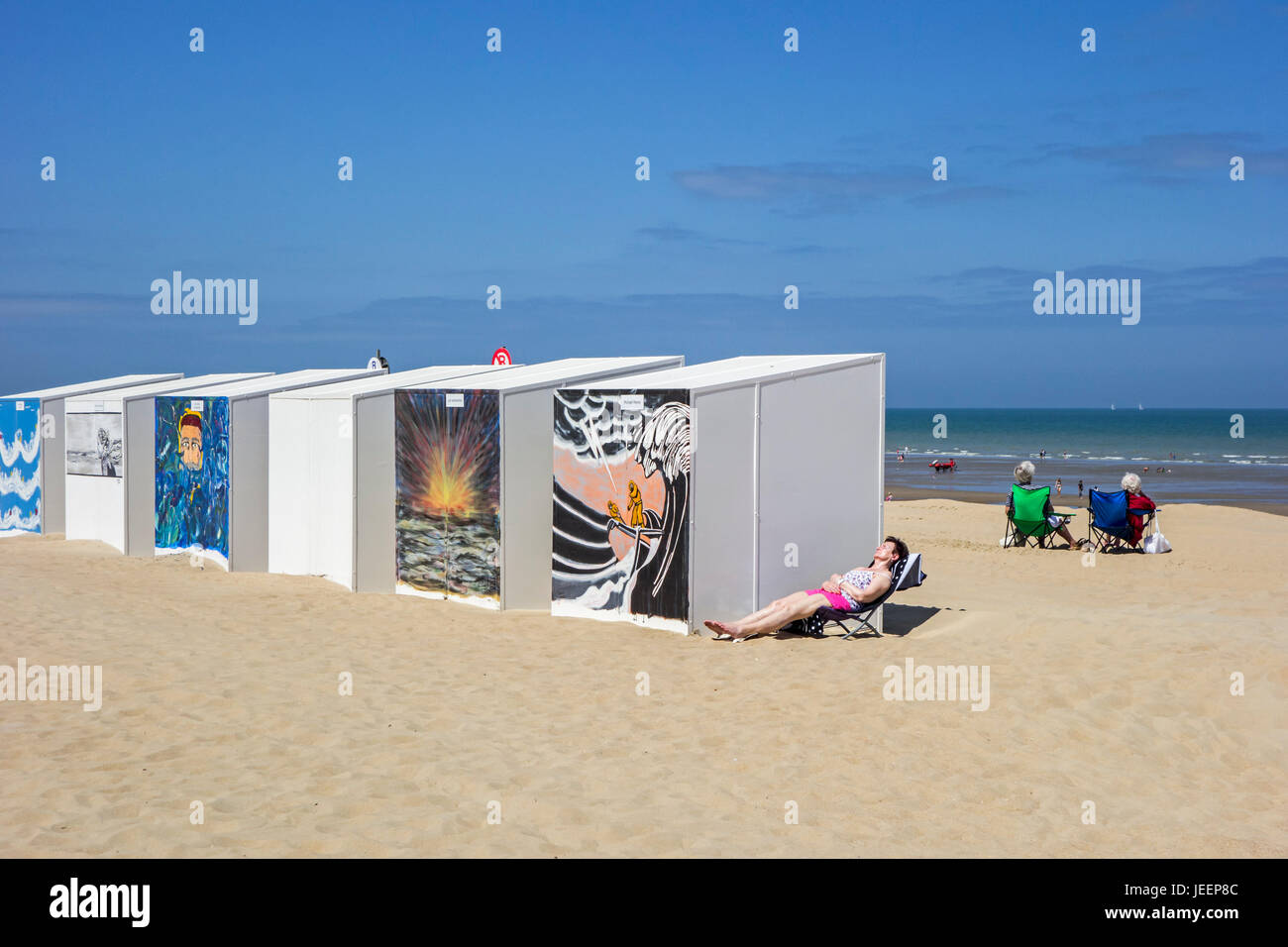 Strandkabinen und ältere Frauen Sonnen am Strand entlang der Nordseeküste dekoriert Stockfoto