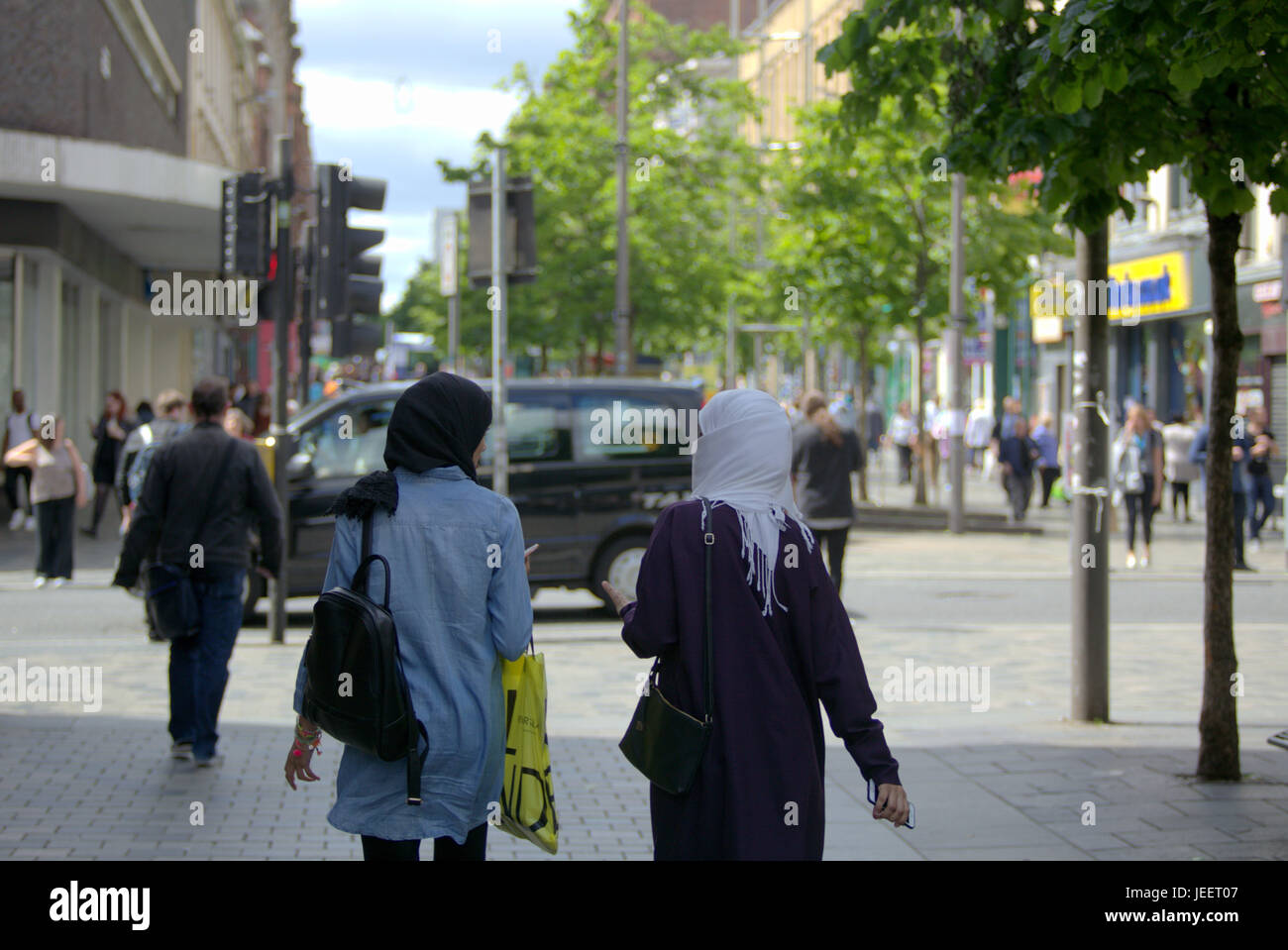 Asiatische Familie Flüchtling gekleidet Hijab Schal auf Straße in der UK alltägliche Szene zwei junge Mädchen einkaufen Stockfoto