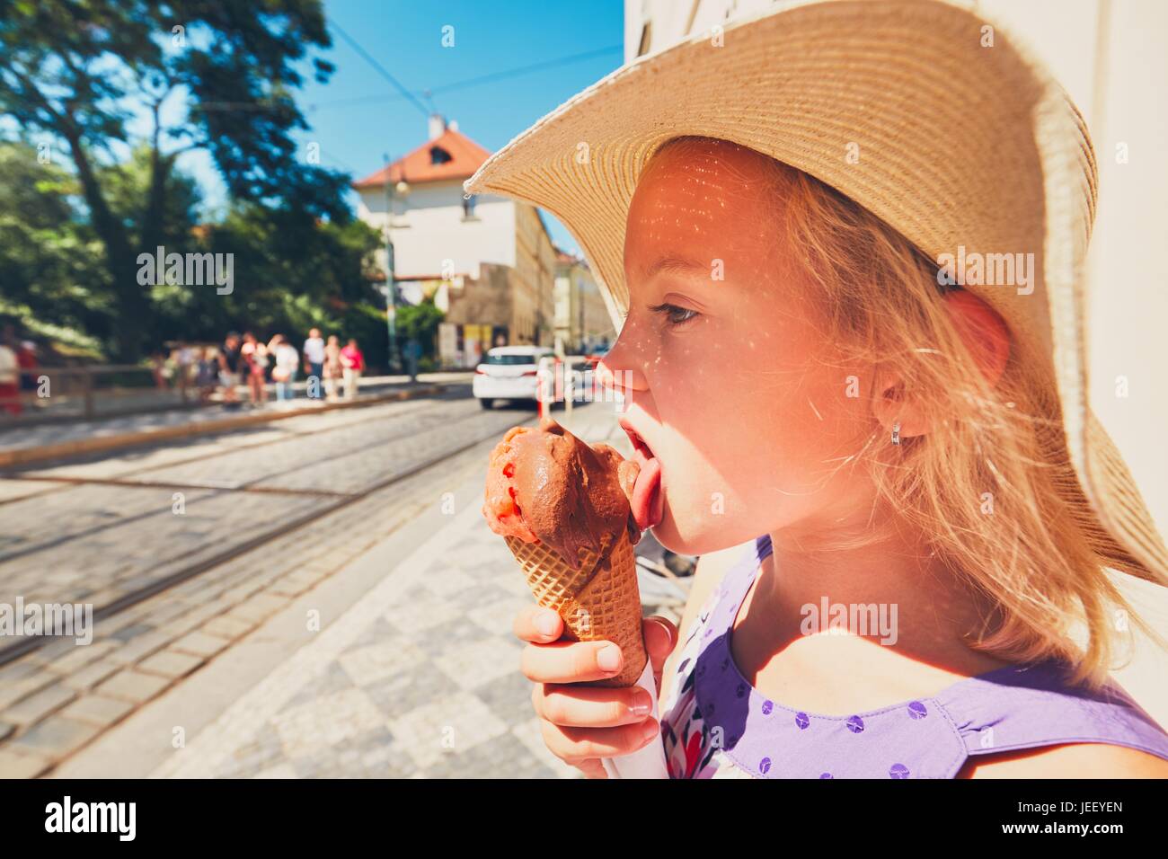 Sommertag in der Stadt. Niedliche kleine Mädchen mit Hut große Eis essen Stockfoto