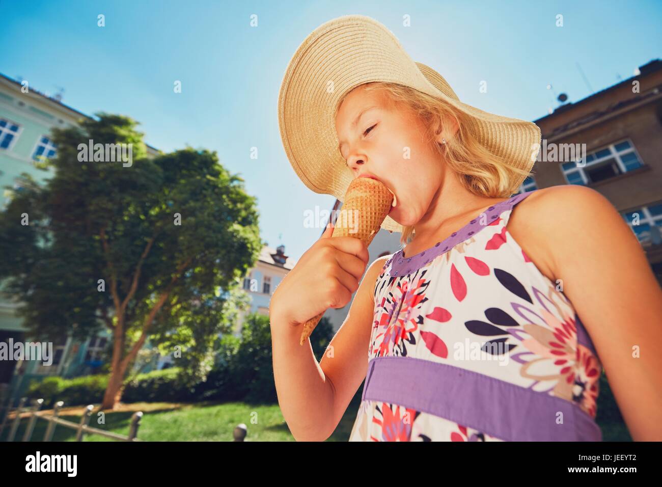 Sommertag in der Stadt. Niedliche kleine Mädchen mit Hut große Eis essen Stockfoto