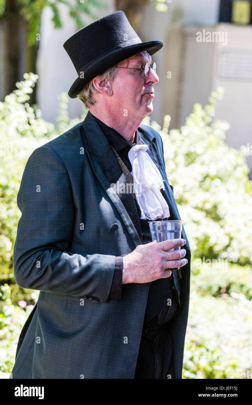 Outdoor, Portrait eines Mannes mittleren Alters, 40s, tragen steampunk Anzug  und Hut mit Krawatte. Holding Bier Glas in der Hand. Von der Seite  Stockfotografie - Alamy