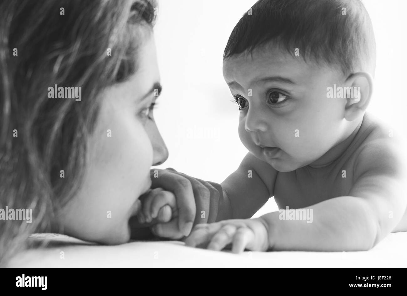 Modell veröffentlichte Foto von einen kleinen Jungen auf seinem Bauch, betrachtet man ihre Mutter vor einem weißen Hintergrund Stockfoto