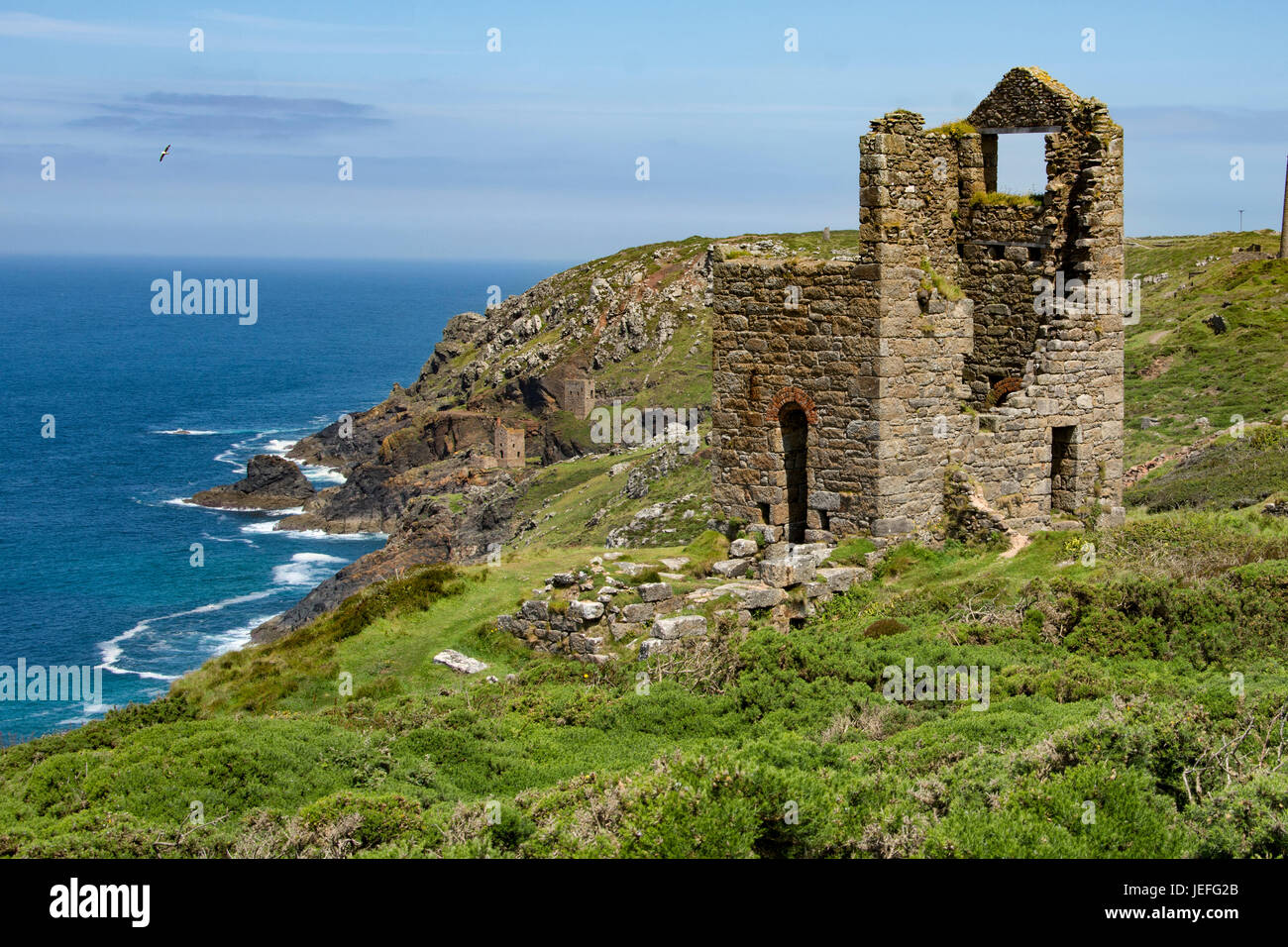 Die zerklüftete Landschaft Cornwalls bei St Just zeigt die alte mine Funktionsweise und Motor Häuser auf den Klippen unter blauem Himmel und mit ruhiger See Stockfoto