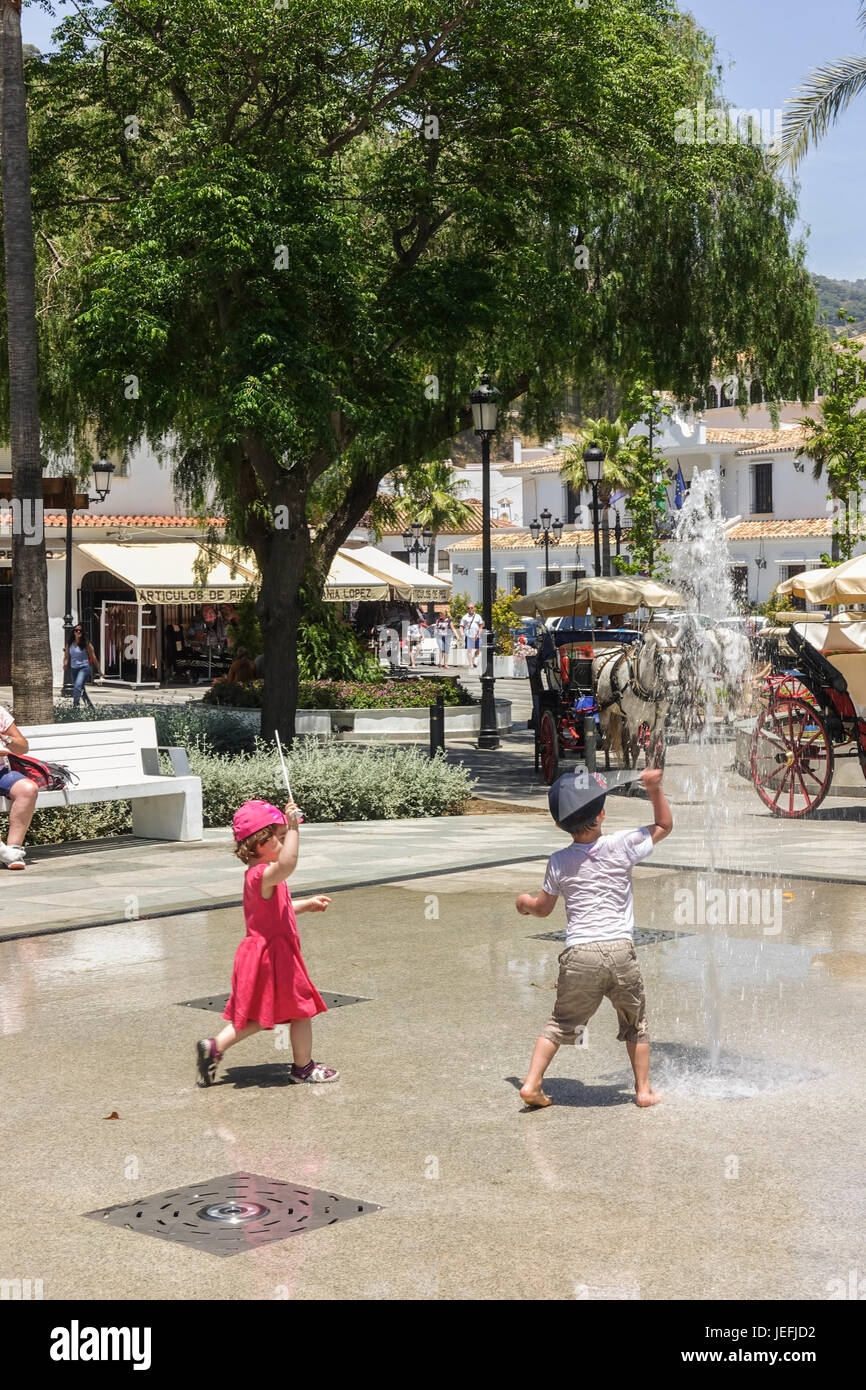 Kinder, Kleinkinder, spielen mit Wasserfontänen an heißen Tag im spanischen Dorf, Mijas Costa Del Sol, Spanien. Stockfoto