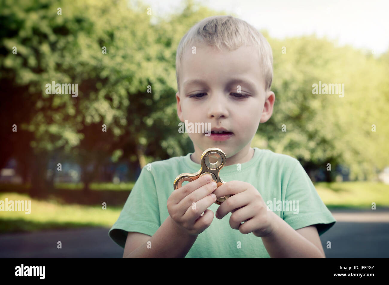 Kleiner Junge mit einem Fidget Spinner im Freien. Spinner zappeln Kind Stress ADHS Aufmerksamkeit Modeerscheinung junge Konzept Stockfoto