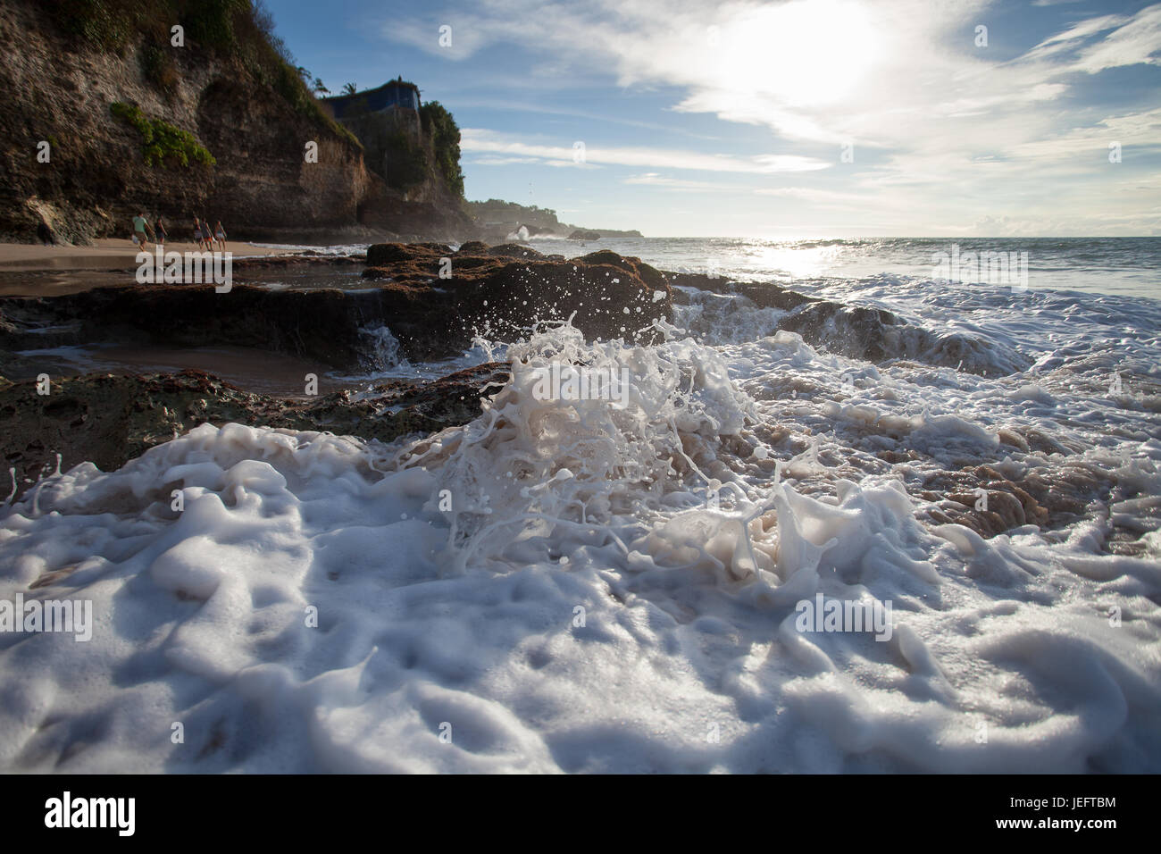 Ocean Wave mit Schaum schlagen gegen die Felsen bei Sonnenuntergang Stockfoto