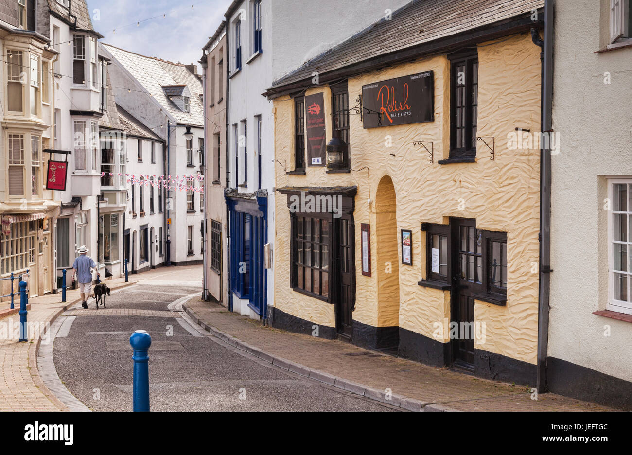 14. Juni 2017: Ilfracombe, North Devon, England, UK - ein Mann geht mit seinem Greyhound unten Vorderstraße, früher die wichtigste Straße der Stadt. Stockfoto